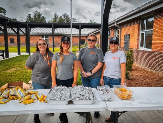 Megan McReynolds, Olivia Harris, Sam Cole, and Robin Kurtz preparing hot dogs for a local elementary school field day